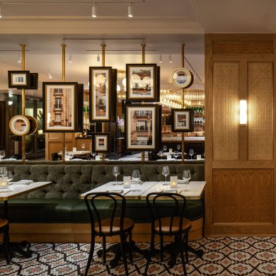 Counter and ceiling mounted brass posts supporting framed pictures as a room divider