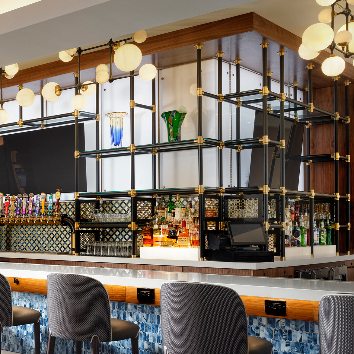 Counter & ceiling mounted Studio style Bistro Designer Shelving configuration in Satin brass and matte black in the bar at Hilton New Orleans Airport LaSalle