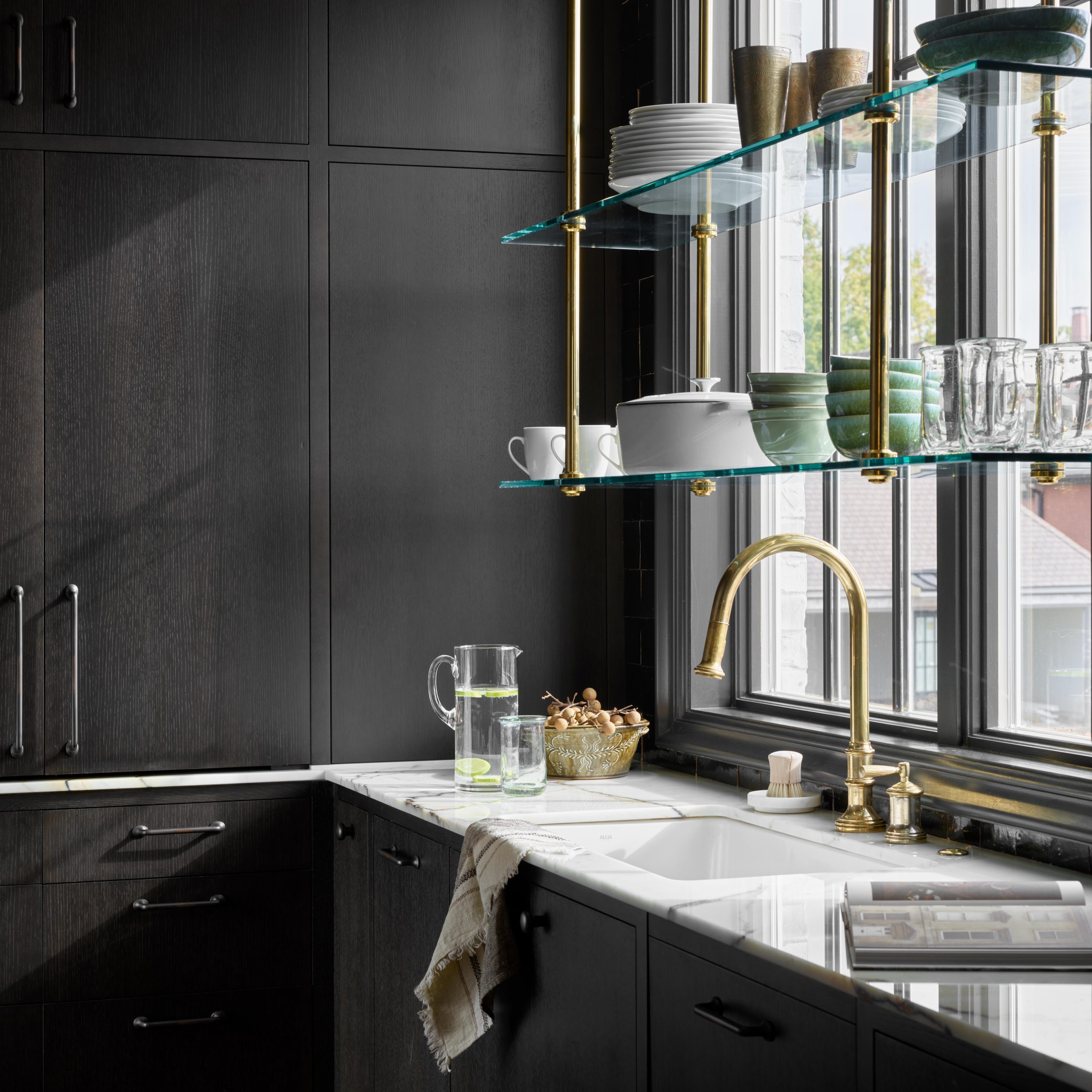 Ceiling-mounted Split Collar style Bistro Designer Shelving with Button style Finials in polished brass with glass shelves in front of a window