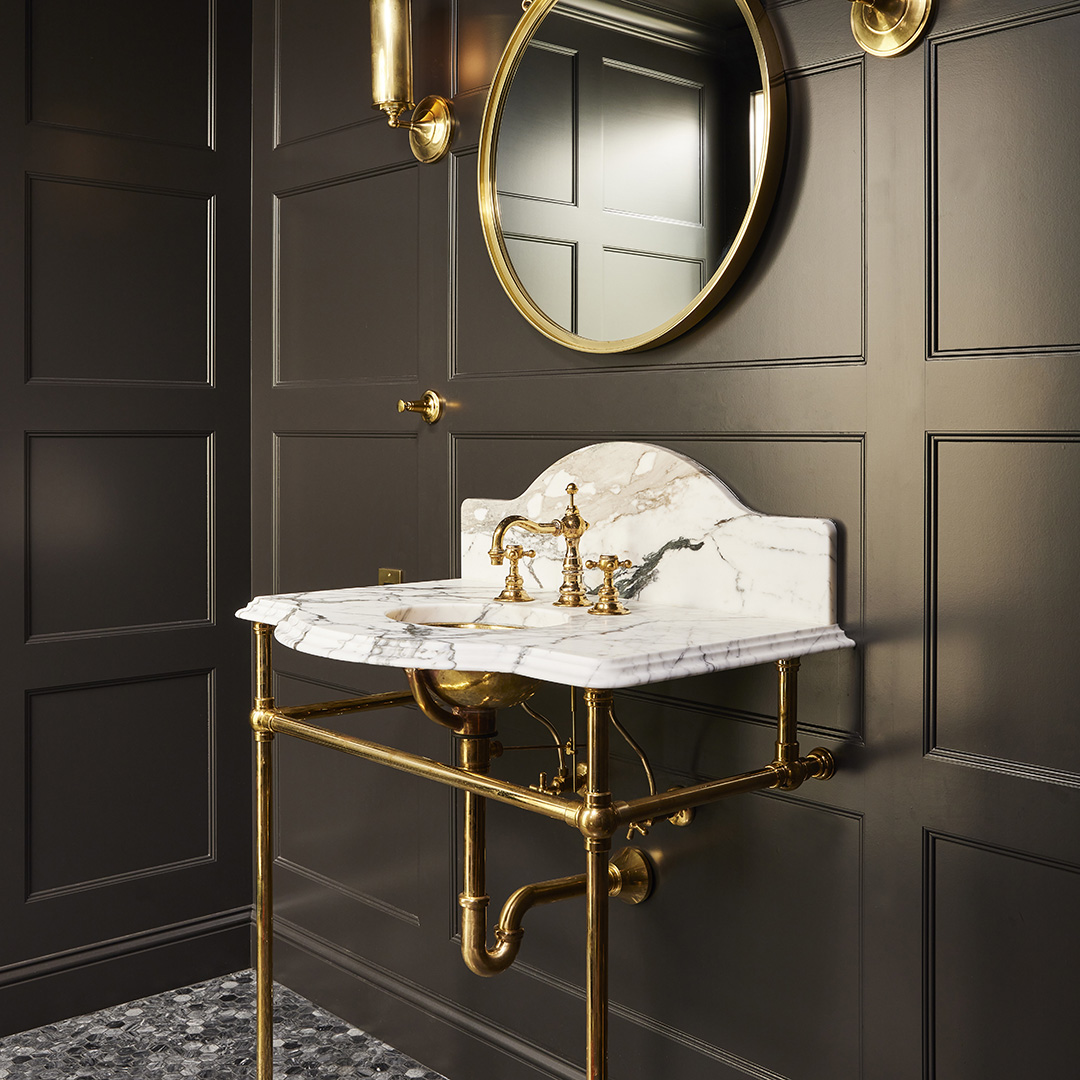 Tapered Foot style Vanity Leg System in polished brass with marbled top in dark gray paneled bathroom