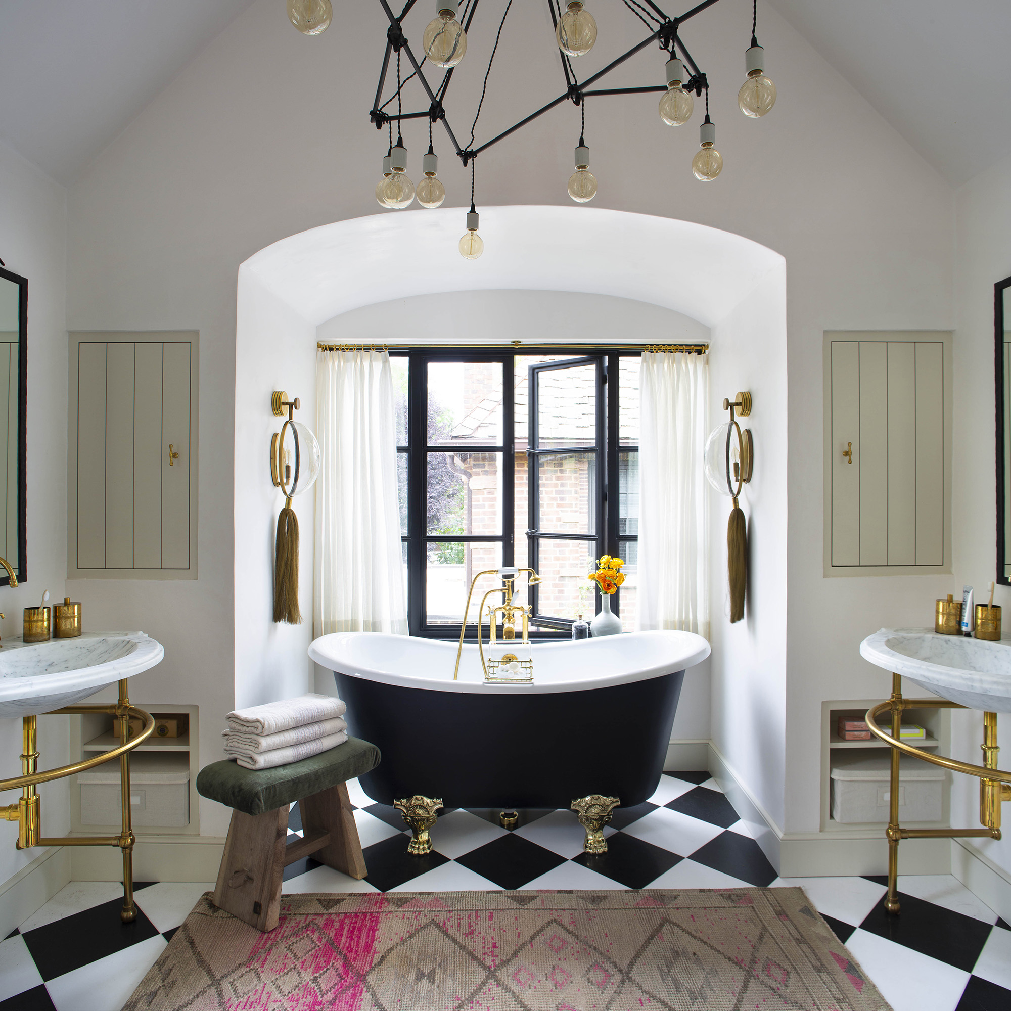 A pair of Petite Renaissance Vanity Leg Systems in aged brass with Stone Forest marble sinktops and a classic claw-foot tub.