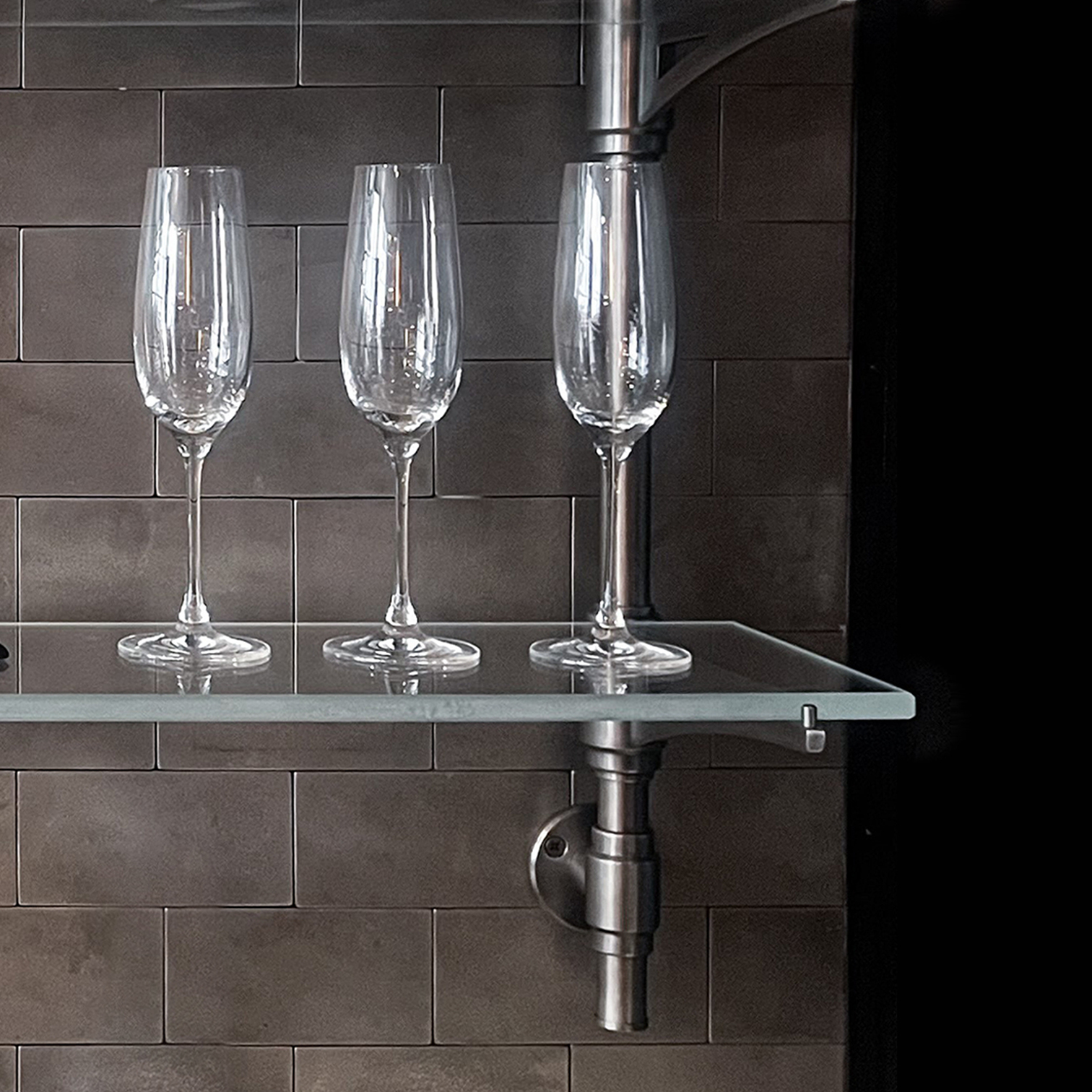 Rack style, wall mounted shelving in Aged Nickel finish with wine glasses on a glass shelf